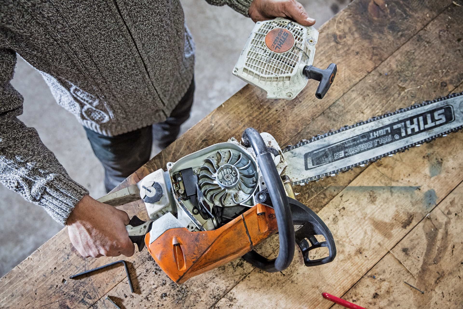 A person performing maintenance work on a STIHL MS 462 C-M petrol-driven chainsaw on a workbench